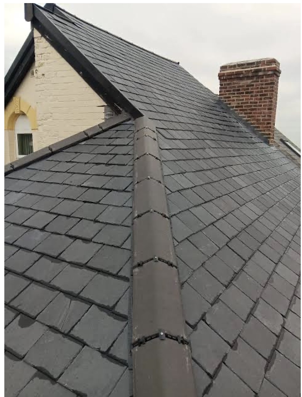 Natural slate roof with half round ridge tiles and brick chimney